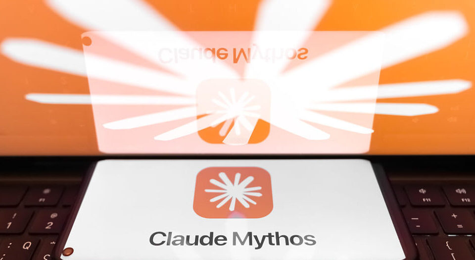 Article Image - Best AI Tools Card displaying the Claude Mythos logo with an orange sunburst emblem on a white card, reflected on a glossy surface near a keyboard