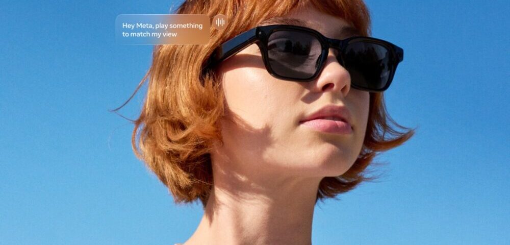 Article Image - Best AI Tools Woman with short red hair and black sunglasses outdoors against a blue sky; a speech bubble reads 'Hey Meta, play something to match my view'.