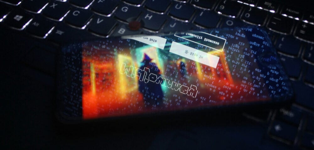 Article Image - Best AI Tools Smartphone with neon digital graphics resting on a dark laptop keyboard, glow reflecting on the keys