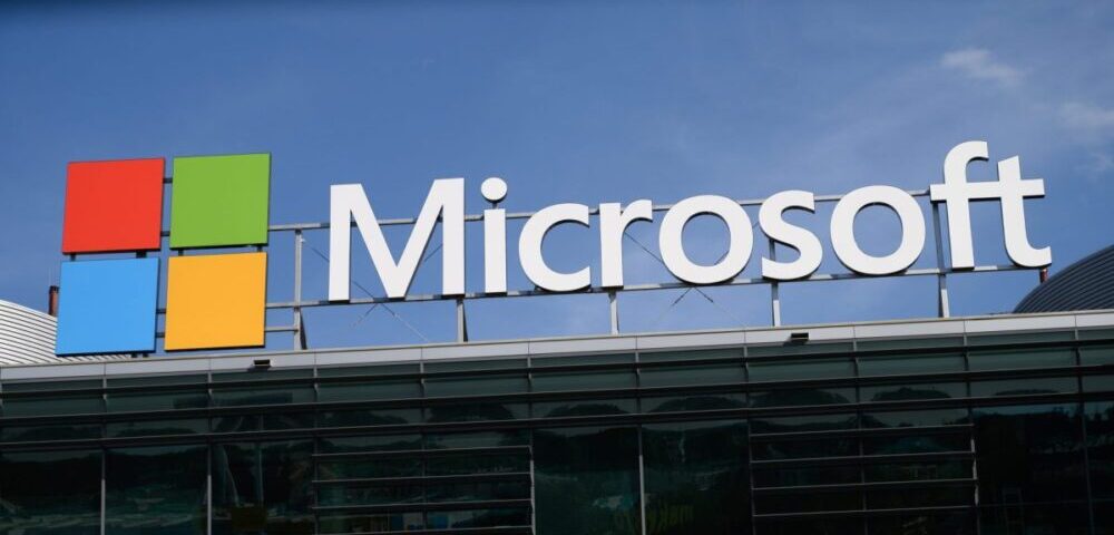 Article Image - Best AI Tools Microsoft signage with a colorful four-square logo on a modern glass building against a blue sky.